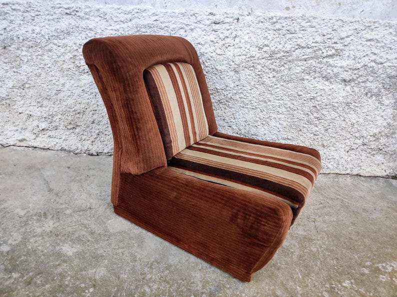 May include: A brown corduroy armchair with a striped cushion. The chair has a curved back and a wide seat.