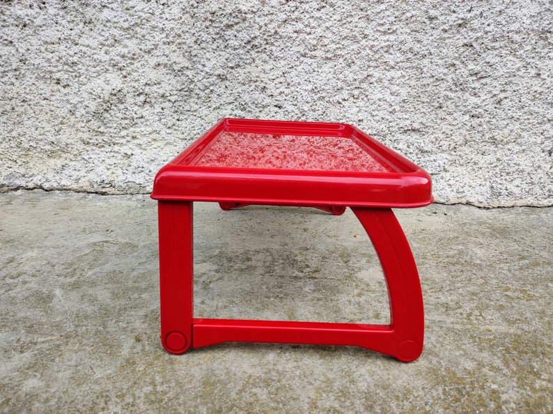K&ouml;nnte beinhalten: Kleiner, rechteckiger Tisch in leuchtendem Rot mit strukturierter Oberfl&auml;che. Der Tisch hat ein einzigartiges Design mit gebogenen Beinen und misst ca. 46 cm lang, 30 cm breit und 20 cm hoch.