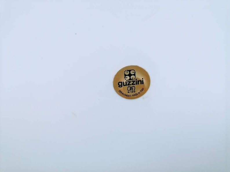 Może przedstawiać: Złota naklejka z tekstem "Guzzini" i słowami "Forniture Made in Italy" w k&oacute;łku.