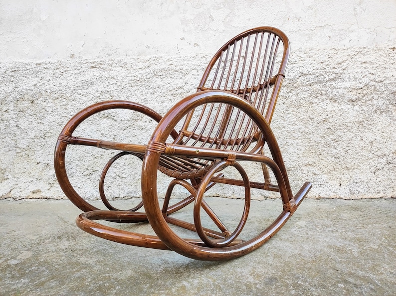 Puede incluir: Una mecedora de mimbre marr&oacute;n con respaldo curvo y asiento ancho. La silla est&aacute; hecha de materiales naturales y tiene un aspecto r&uacute;stico.