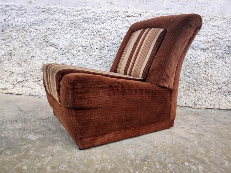 May include: A brown corduroy armchair with a striped beige and brown cushion. The chair has a low back and a wide seat.