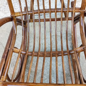 Puede incluir: Primer plano de una mecedora de mimbre marr&oacute;n con acabado brillante. La silla est&aacute; hecha de mimbre tejido y tiene un respaldo y un asiento curvos.