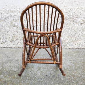 Puede incluir: Una mecedora de mimbre marr&oacute;n con respaldo curvo y asiento tejido. La silla est&aacute; hecha de materiales naturales y tiene un aspecto r&uacute;stico.