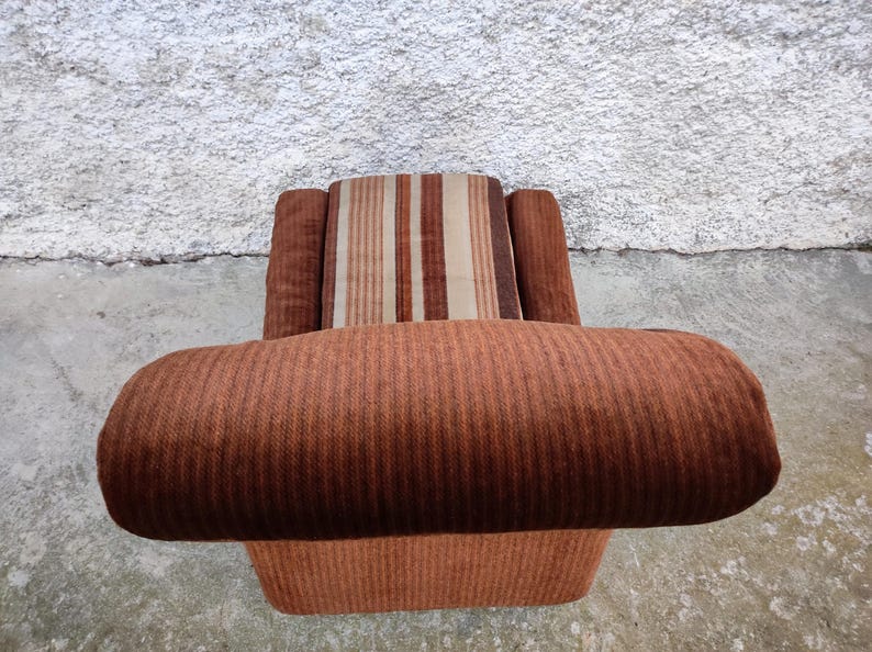 May include: A brown striped armchair with a brown and white striped cushion. The chair has a high back and wide arms.