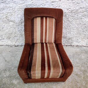 May include: A brown striped armchair with a high back and a thick, padded seat. The chair is upholstered in a brown and white striped fabric.