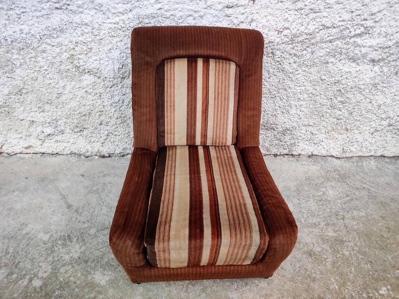 May include: A brown striped armchair with a high back and a thick, padded seat. The chair is upholstered in a brown and white striped fabric.