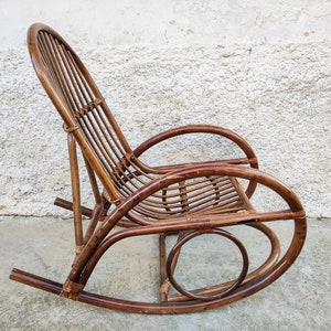 Puede incluir: Una mecedora de mimbre marr&oacute;n con respaldo curvo y asiento redondeado. La silla est&aacute; hecha de rat&aacute;n tejido natural y tiene un aspecto r&uacute;stico y vintage.