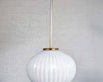 May include: A white, ribbed glass pendant light fixture with a gold metal rod and ceiling mount.