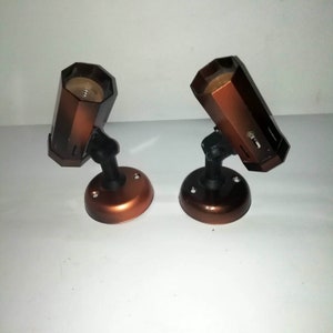 May include: Two brown metal light fixtures with black adjustable arms and a white background.