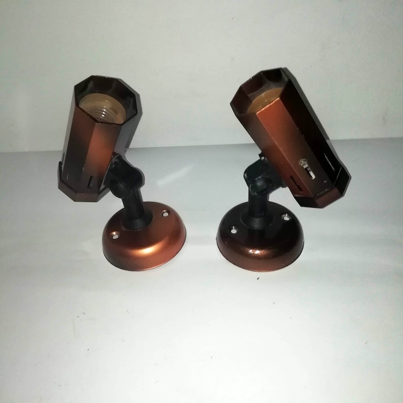 May include: Two brown metal light fixtures with black adjustable arms and a white background.