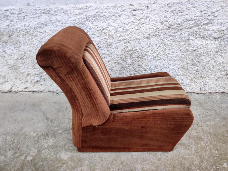May include: A brown corduroy armchair with a striped pattern in shades of brown, beige, and white. The chair has a high back and a curved seat.