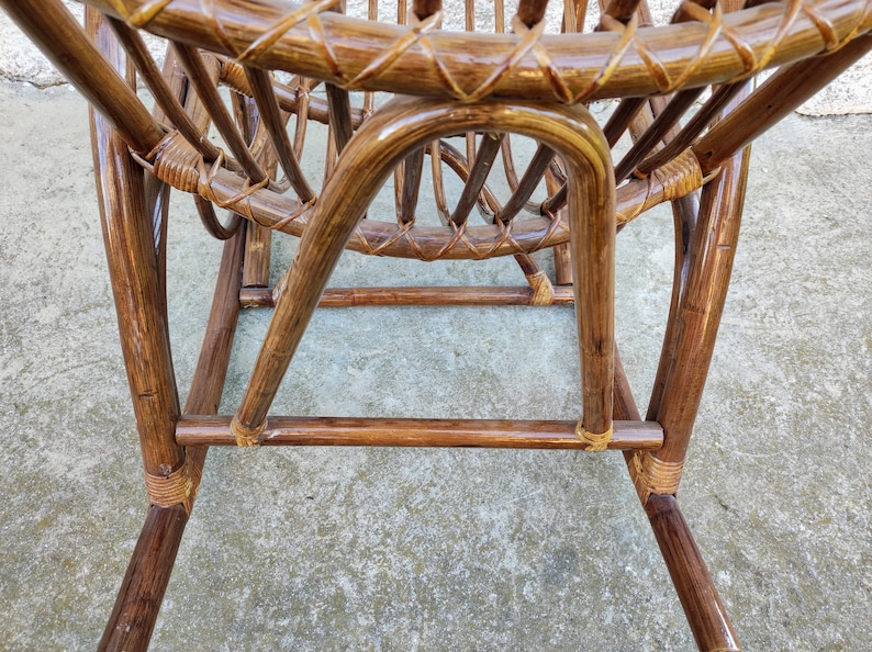 Puede incluir: Una mecedora de mimbre marr&oacute;n con asiento y respaldo tejidos. La silla est&aacute; hecha de materiales naturales y tiene un aspecto r&uacute;stico.