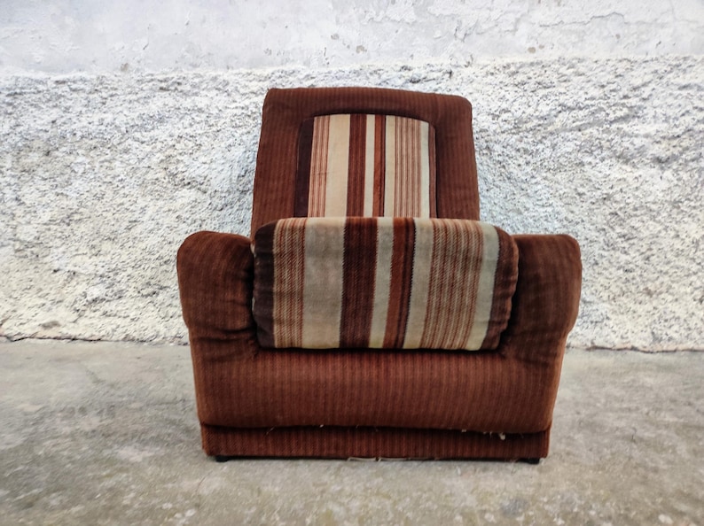 May include: A brown striped armchair with a high back and thick padding. The chair has a brown corduroy fabric with a striped pattern in shades of brown, beige, and white.