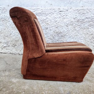 May include: A brown corduroy armchair with a striped seat cushion. The chair has a high back and a curved shape.