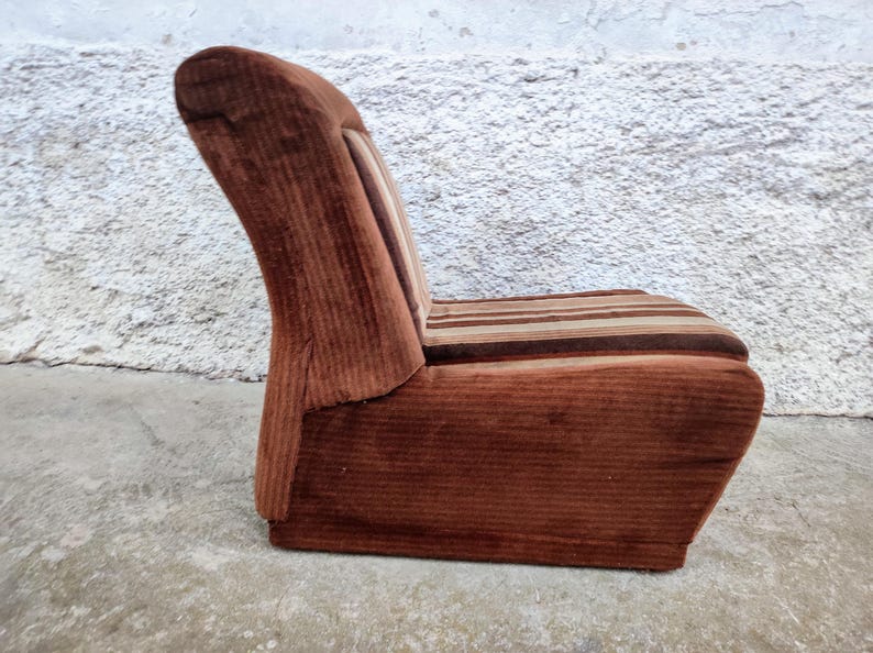 May include: A brown corduroy armchair with a striped seat cushion. The chair has a high back and a curved shape.