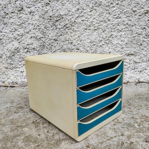 Peut inclure: Un organiseur de bureau vintage crème avec quatre tiroirs turquoise. Le dessus arrondi et les poignées de tiroir ajoutent une esthétique rétro. L'organisateur est en matériau robuste, idéal pour le bureau ou la maison.
