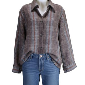 May include: A brown plaid button-down shirt with blue, red, and gray stripes. The shirt is displayed on a mannequin and paired with blue jeans. The shirt has a collared neckline and long sleeves.