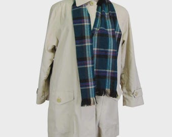 May include: A beige trench coat with a teal, black, and purple plaid scarf. The coat has a collared neckline, button closures, and two front pockets. The scarf is draped around the neck.