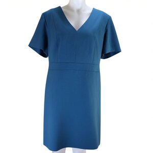 May include: A teal-colored dress with a V-neckline and short, flared sleeves. The dress features a fitted waist and a knee-length hemline. The fabric appears smooth and has a slight sheen. The dress is displayed on a mannequin.