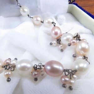 May include: A white ceramic mug with a black handle and the text "But First, Coffee" in a bold, black font. The mug is set against a blurred background, suggesting a cozy setting.