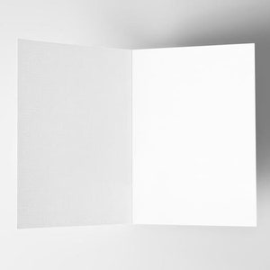 Pu&ograve; includere: Un biglietto bianco vuoto piegato a met&agrave;, con una superficie testurizzata. Il biglietto &egrave; su uno sfondo bianco.