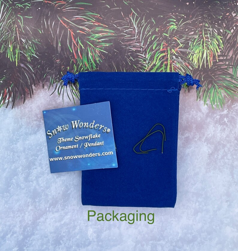 May include: A blue velvet pouch with a white card that says "Snow Wonders Theme Snowflake Ornament/Pendant www.snowwonders.com" and the word "Packaging" printed below the pouch.