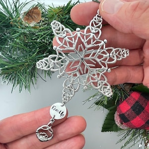 May include: Silver snowflake ornament with a delicate design and a round charm that says "Family".