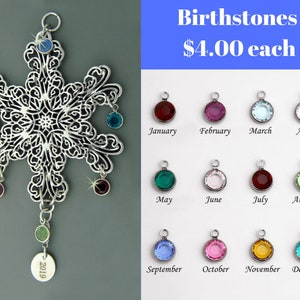 May include: A silver snowflake ornament with 12 dangling birthstone charms. The charms are in various colors, including red, blue, green, and pink. The ornament also has a silver tag with the year 2019 engraved on it. Birthstones are $4.00 each.