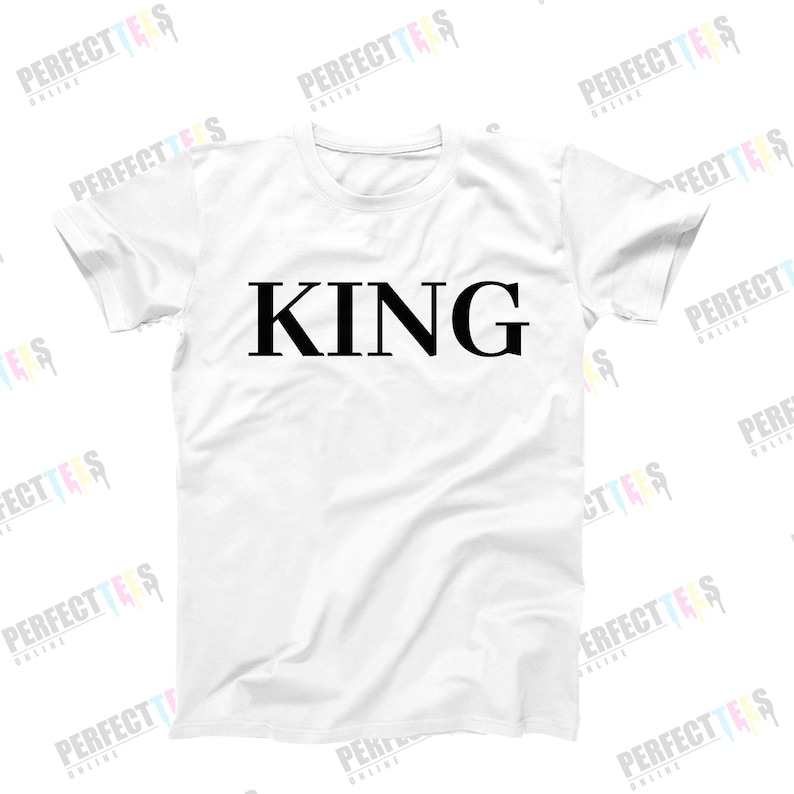May include: White t-shirt with the word "KING" printed in black on the front.