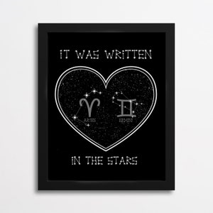 Puede incluir: Impresión gráfica en blanco y negro con una forma de corazón llena de estrellas y los signos del zodíaco Aries y Géminis. El texto "It was written in the stars" está debajo del corazón.
