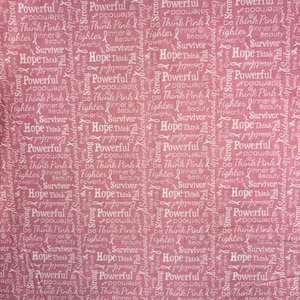 May include: Pink fabric with white text including words like "Hope," "Powerful," and "Survivor." The fabric features a repeating pattern of words and pink ribbons, creating a supportive theme.