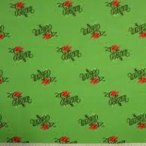 May include: Green fabric with a repeating pattern of red roses and the text "Wild Roses" in black script. A ruler with inch measurements is at the bottom of the image.