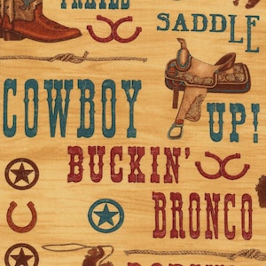 Pode incluir: Um tecido com tema western com uma bota de cowboy, sela, ferraduras e corda. As palavras "Cowboy Up!" e "Buckin' Bronco" são exibidas em letras azuis e vermelhas sobre um fundo castanho claro.
