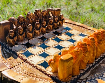 May include: A wooden chess set with intricately carved pieces. The pieces are arranged on a wooden chessboard with a black and white checkered pattern. The chessboard has a decorative border.