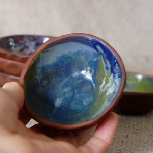 May include: Set of four small ceramic bowls with a blue, green, and white glaze. The bowls are handmade and have a rustic, earthy feel.