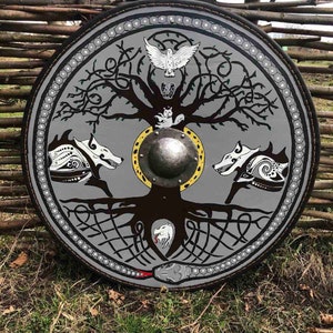 Könnte beinhalten: Ein runder, grauer Schild mit einem schwarzen und weißen Baum des Lebens-Design. Der Baum hat einen weißen Vogel, einen weißen Wolf und eine schwarze Schlange. Der Schild hat einen Metall-Mittelboss.