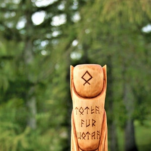 May include: A wooden totem carved with runes and the words "Totem Fur Wotan". The totem is a light brown color and has a smooth finish.