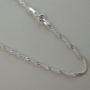 May include: A silver chain necklace with a twisted rope design.