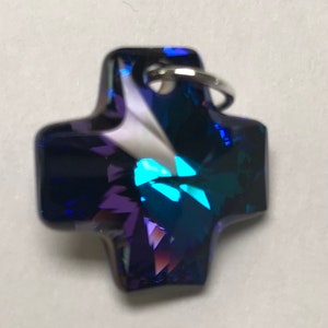 May include: A small, blue crystal cross charm with a silver loop for attaching to a necklace or bracelet.