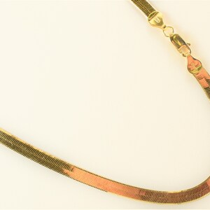 May include: A gold snake chain necklace with a clasp.
