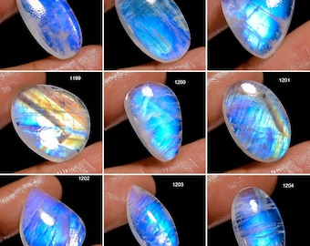 May include: A collection of nine oval and teardrop-shaped moonstone cabochons with iridescent blue and white colors. The stones are displayed on a white background.