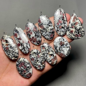 Può includere: Dieci cabochon ovali di rubino rosso in matrice, un tipo di pietra preziosa, con sfondo bianco e nero. Le pietre sono numerate da 1 a 10.