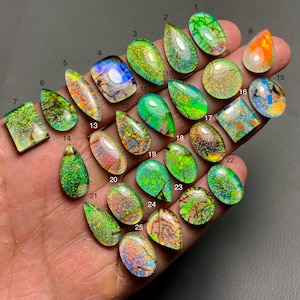 May include: Twenty-five iridescent opal cabochons in various shapes and sizes, including teardrop, oval, and square. The opals are a mix of green, blue, and orange colors.