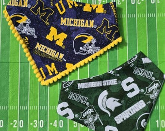 May include: Two bandanas, one navy blue with yellow accents and the text "MICHIGAN" and "M", the other green with white text "MICHIGAN STATE" and "MSU". Both are on a green background.