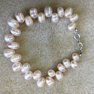 May include: A pearl bracelet with a silver clasp. The bracelet is made of white pearls and is approximately 18 inches long.