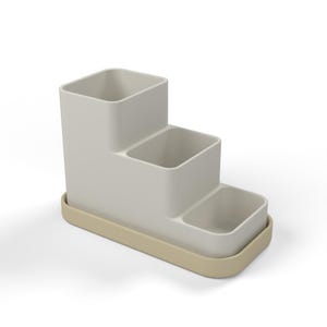 May include: A tiered desk organizer featuring three rectangular compartments of varying heights in a light gray finish, set upon a solid, rounded rectangular base in a contrasting light beige color for stable storage.