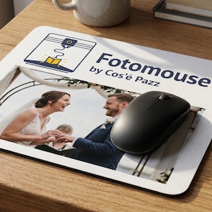 Può includere: Un tappetino per mouse bianco con una foto di matrimonio e il testo "Fotomouse by Cos'e Pazz". Un mouse wireless nero è posizionato sul tappetino. Una tastiera e una tazza sono sullo sfondo.