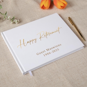 May include: A white rectangular guest book with gold foil lettering that reads Happy Retirement, Geert Maswiens, 1986-2025. The book is accompanied by a gold metallic pen, and the cover features a clean, smooth finish with a small white ribbon bookmark.
