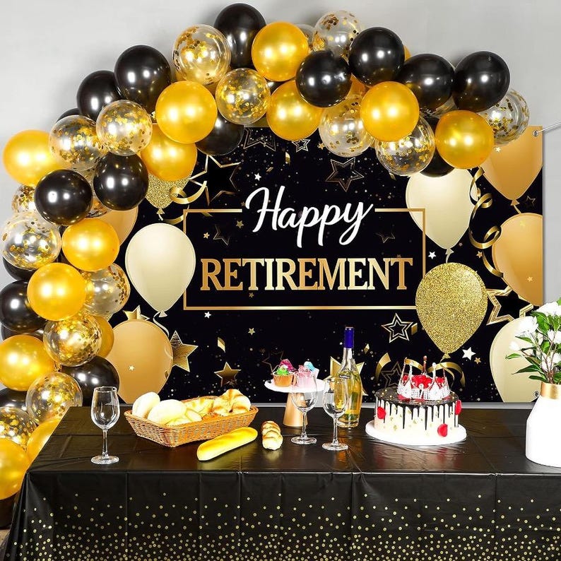 May include: A black and gold Happy Retirement backdrop banner decorated with an arch of black, gold, and clear confetti-filled balloons. A table covered in a black tablecloth with gold dots holds a cake, wine bottle, glasses, and bread.