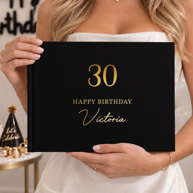May include: A rectangular black photo album with gold foil text on the front cover. The cover features the number 30 at the top, followed by the words HAPPY BIRTHDAY and the name Victoria in a cursive script font centered below the text.
